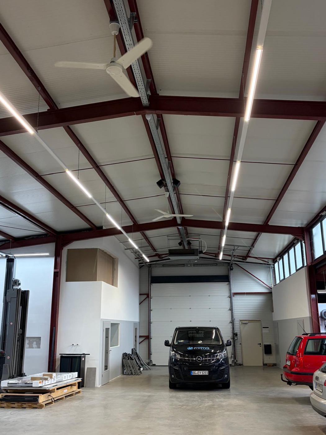 Beleuchtete Gewerbehalle mit LED-Lichtbändern und Deckenventilatoren